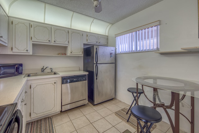 kitchen with a textured ceiling, stainless steel appliances, light tile floors, and sink