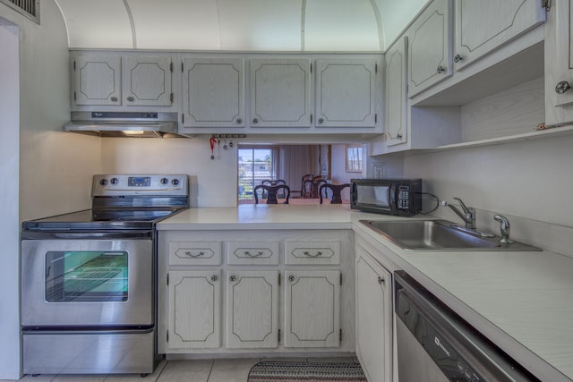 kitchen with wall chimney range hood, stainless steel appliances, sink, and light tile flooring