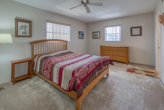 bedroom with ceiling fan, carpet, and a textured ceiling