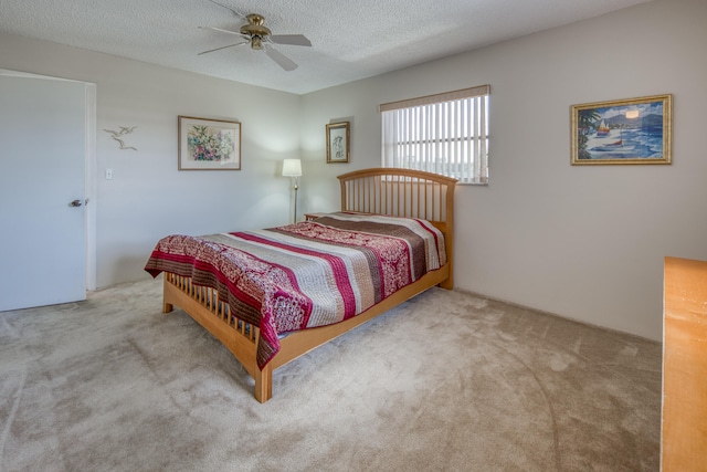 bedroom with ceiling fan, carpet flooring, and a textured ceiling