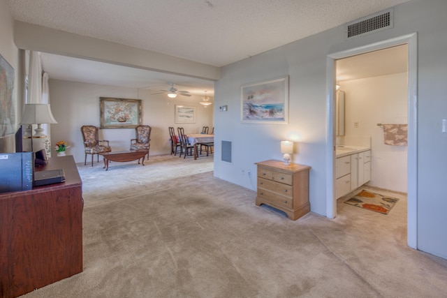 sitting room with light carpet, ceiling fan, and a textured ceiling