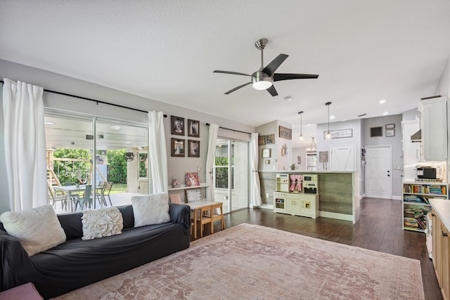 living room with ceiling fan, a healthy amount of sunlight, and dark wood-type flooring