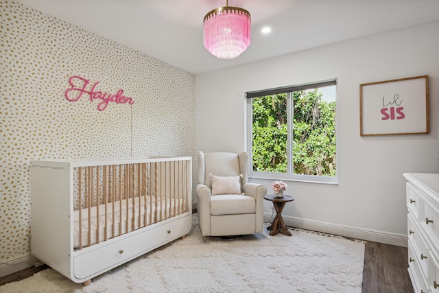 bedroom with light hardwood / wood-style flooring and a nursery area