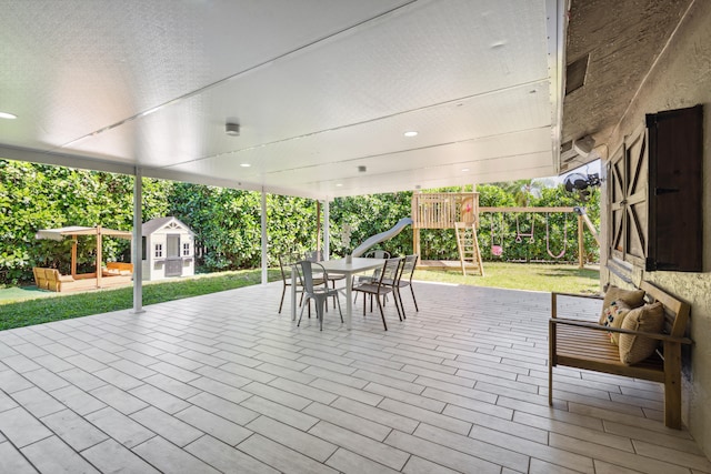 view of patio featuring a playground and a storage shed