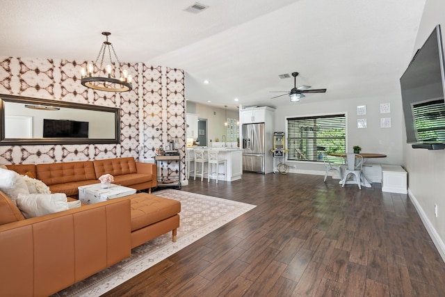 living room with ceiling fan with notable chandelier and dark hardwood / wood-style floors