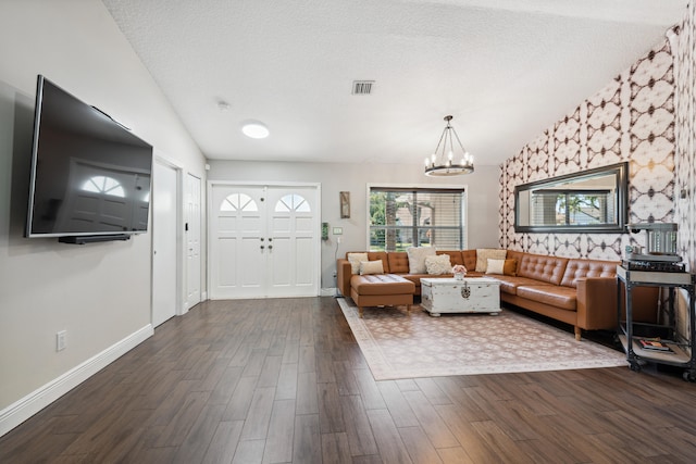 living room with a chandelier, dark hardwood / wood-style floors, and a textured ceiling