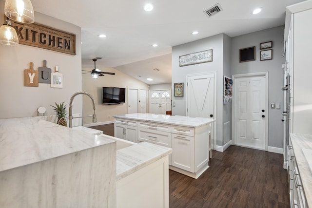 kitchen featuring light stone counters, ceiling fan, white cabinets, hanging light fixtures, and dark hardwood / wood-style floors