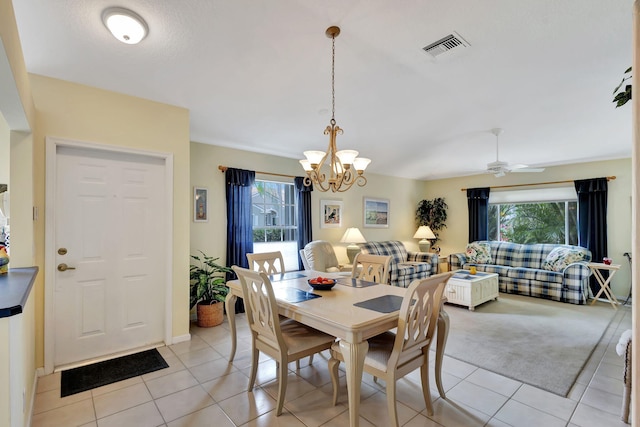 tiled dining room featuring ceiling fan with notable chandelier and a wealth of natural light