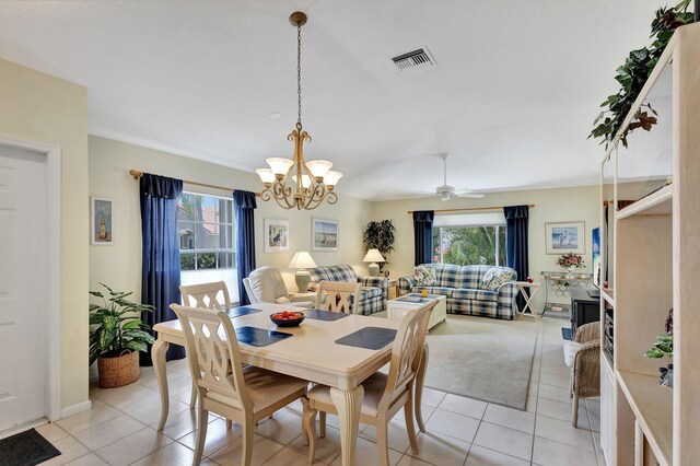 tiled dining room with ceiling fan with notable chandelier and a wealth of natural light