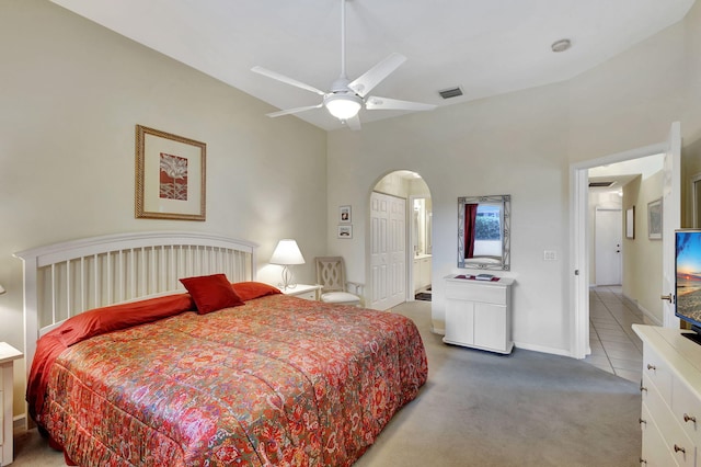 carpeted bedroom featuring high vaulted ceiling, ceiling fan, and ensuite bathroom