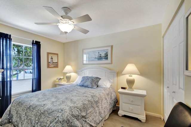 bedroom featuring light colored carpet, a closet, ceiling fan, and a textured ceiling