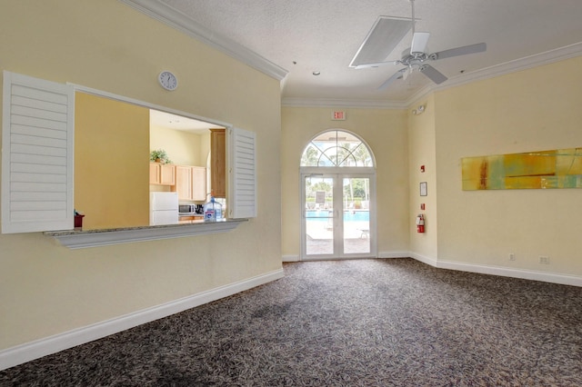 empty room with a textured ceiling, carpet floors, ceiling fan, and crown molding