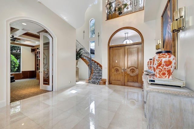 carpeted entrance foyer featuring beam ceiling, a towering ceiling, and coffered ceiling