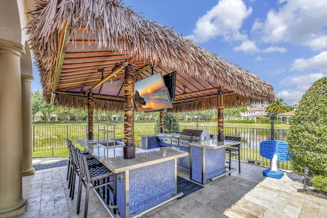 view of patio featuring area for grilling, a water view, a gazebo, and exterior kitchen