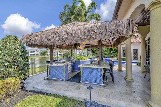 view of terrace featuring a water view, grilling area, and exterior kitchen