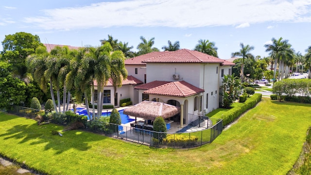 rear view of house with a fenced in pool, a patio, a gazebo, and a lawn