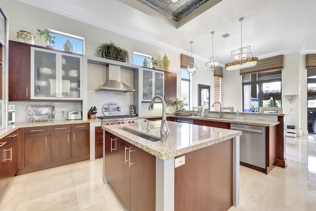 kitchen featuring a healthy amount of sunlight, a center island with sink, and wall chimney exhaust hood