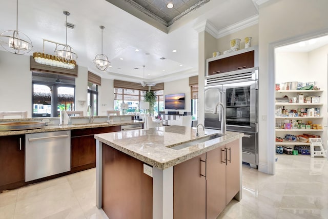 kitchen featuring appliances with stainless steel finishes, an island with sink, light stone counters, light tile floors, and ornamental molding