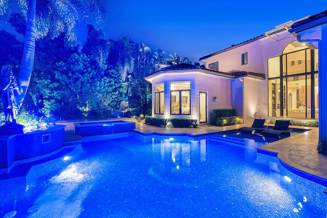 pool at night featuring a patio