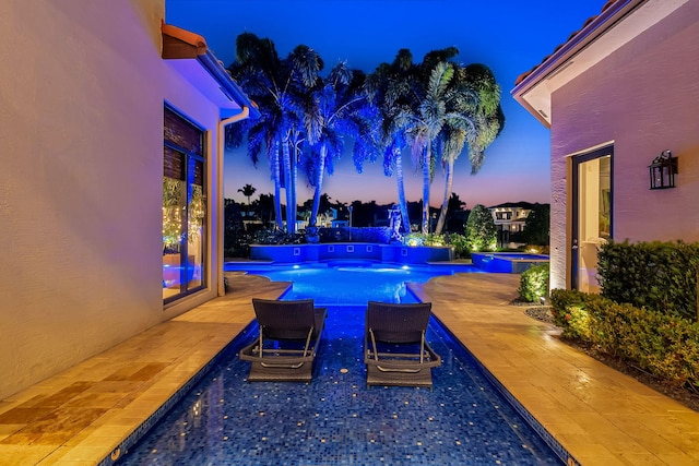 pool at dusk featuring a patio area