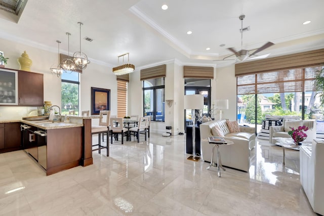 kitchen with light tile floors, ceiling fan with notable chandelier, hanging light fixtures, a kitchen breakfast bar, and light stone countertops