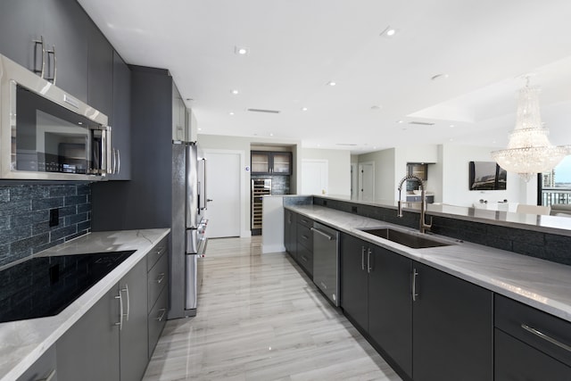 kitchen featuring light hardwood / wood-style floors, backsplash, sink, appliances with stainless steel finishes, and pendant lighting