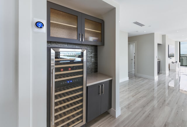 bar featuring beverage cooler and light hardwood / wood-style flooring