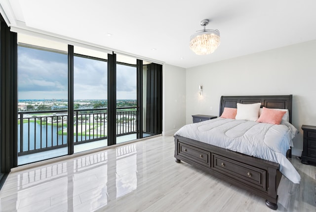 bedroom with access to outside, a chandelier, light wood-type flooring, and expansive windows