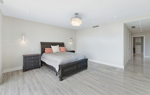 bedroom with a notable chandelier and light wood-type flooring