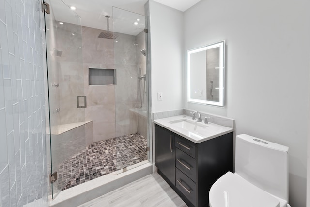 bathroom with a shower with shower door, vanity, and toilet