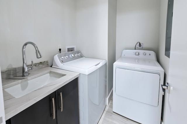 laundry area with washing machine and clothes dryer, electric dryer hookup, cabinets, and light hardwood / wood-style flooring