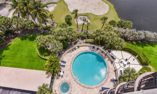 view of pool with a yard, a water view, and a hot tub