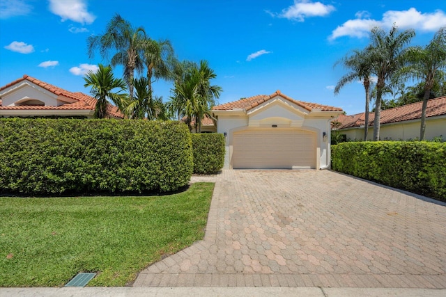 mediterranean / spanish home featuring a garage and a front yard