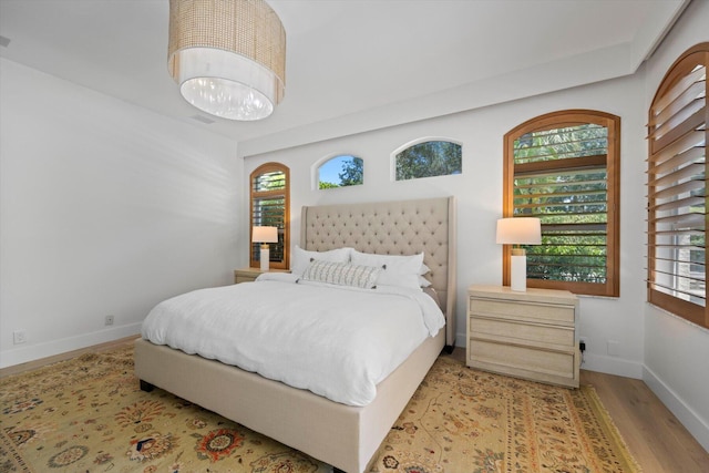 bedroom featuring light hardwood / wood-style flooring, a notable chandelier, and multiple windows