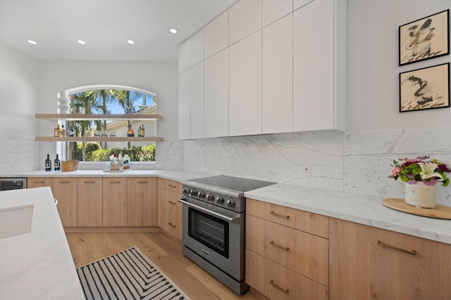 kitchen featuring stainless steel range, light hardwood / wood-style floors, light brown cabinets, and tasteful backsplash