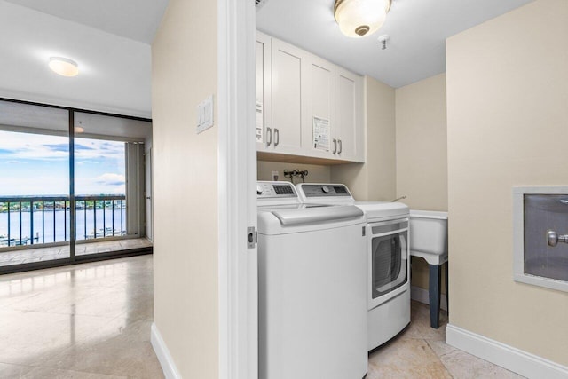 washroom with cabinets, light tile patterned floors, washer and dryer, and a water view