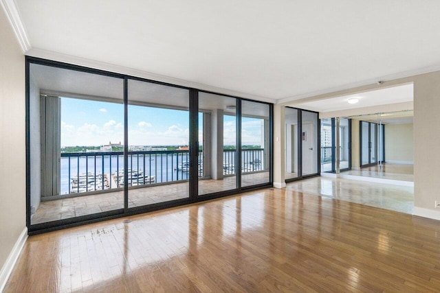 unfurnished room with hardwood / wood-style flooring, ornamental molding, floor to ceiling windows, and a water view