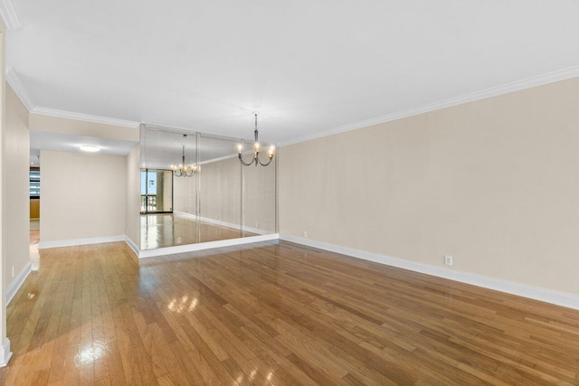 unfurnished room with an inviting chandelier, hardwood / wood-style floors, and ornamental molding