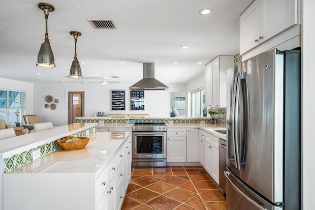 kitchen featuring pendant lighting, island range hood, white cabinets, kitchen peninsula, and stainless steel appliances