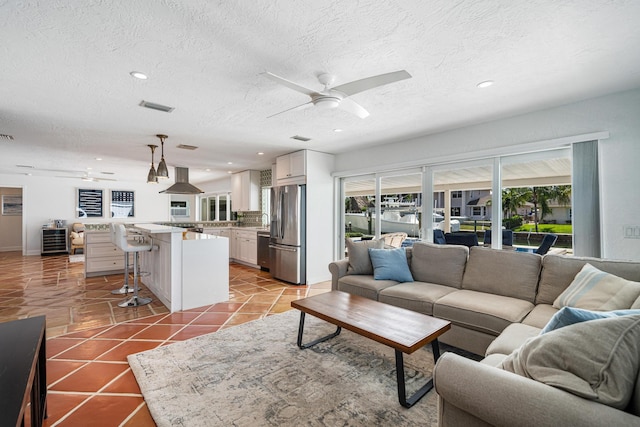 tiled living room featuring a textured ceiling and ceiling fan