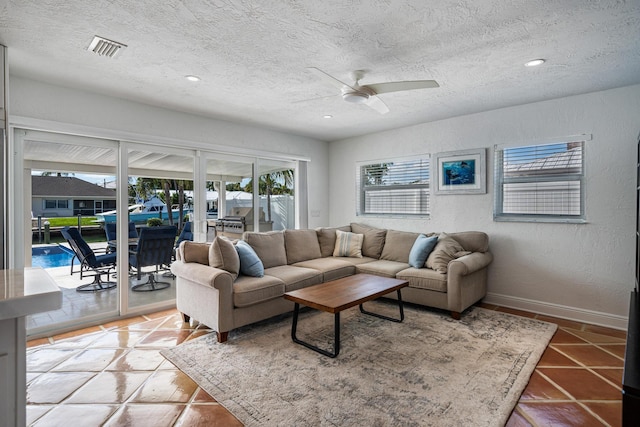 living room featuring ceiling fan, a textured ceiling, and light tile patterned floors