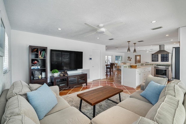 living room featuring ceiling fan, a textured ceiling, and light tile patterned floors