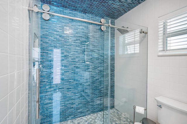 bathroom with tile walls, an enclosed shower, and toilet