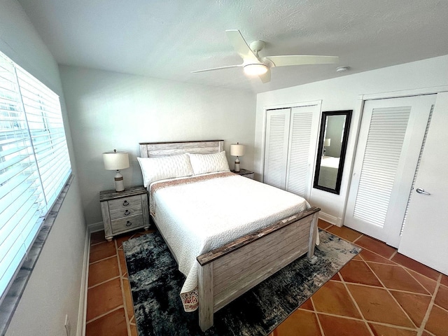 bedroom featuring multiple closets, ceiling fan, and dark tile patterned flooring