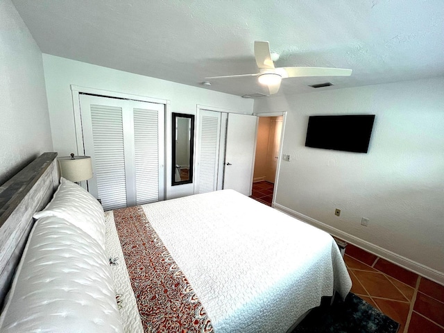 bedroom featuring two closets, a textured ceiling, and ceiling fan