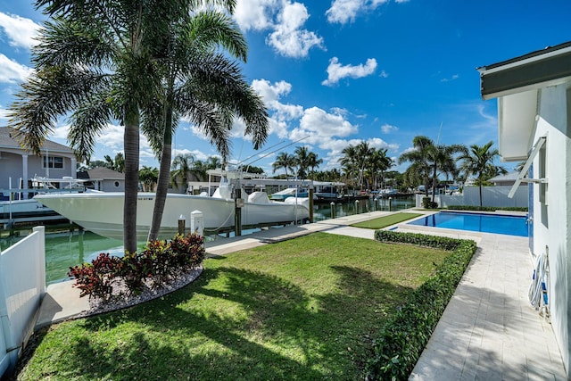 view of yard featuring a fenced in pool, a water view, and a boat dock