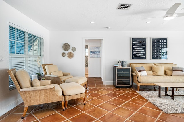 tiled living room with a textured ceiling, beverage cooler, and ceiling fan