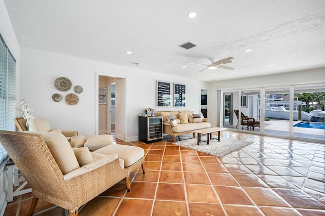 tiled living room featuring ceiling fan, beverage cooler, and a textured ceiling