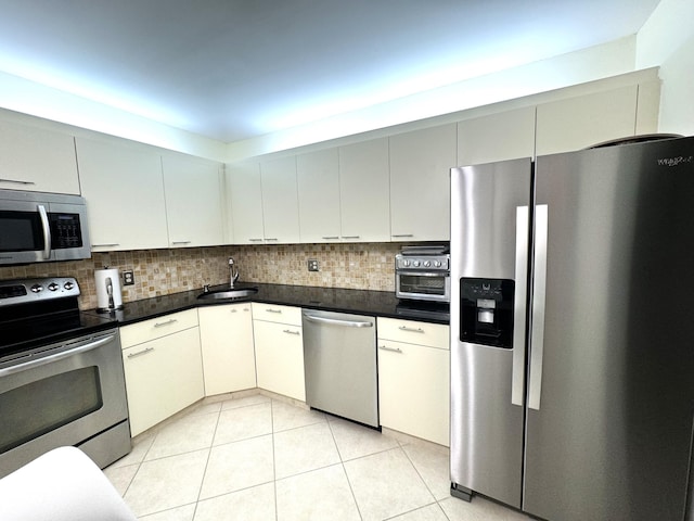 kitchen with tasteful backsplash, sink, light tile patterned flooring, and appliances with stainless steel finishes