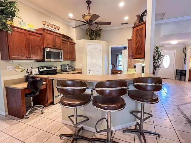 kitchen featuring a kitchen breakfast bar, stainless steel appliances, ceiling fan, and light tile flooring